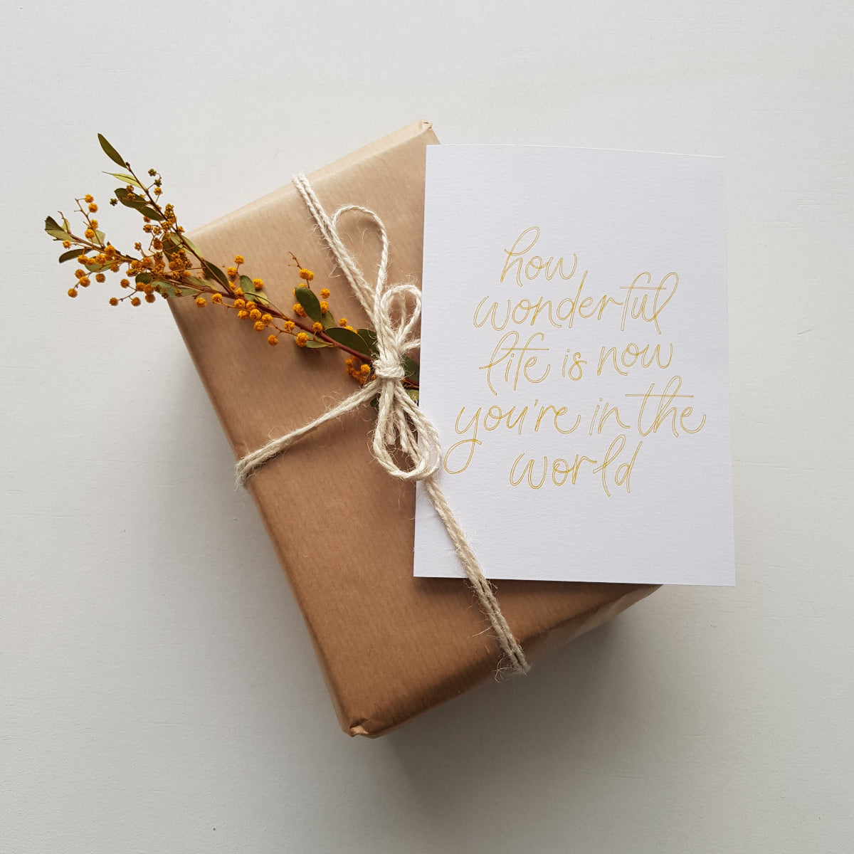 Greeting card with text 'how wonderful life is now you're in the world' in yellow on a brown present
