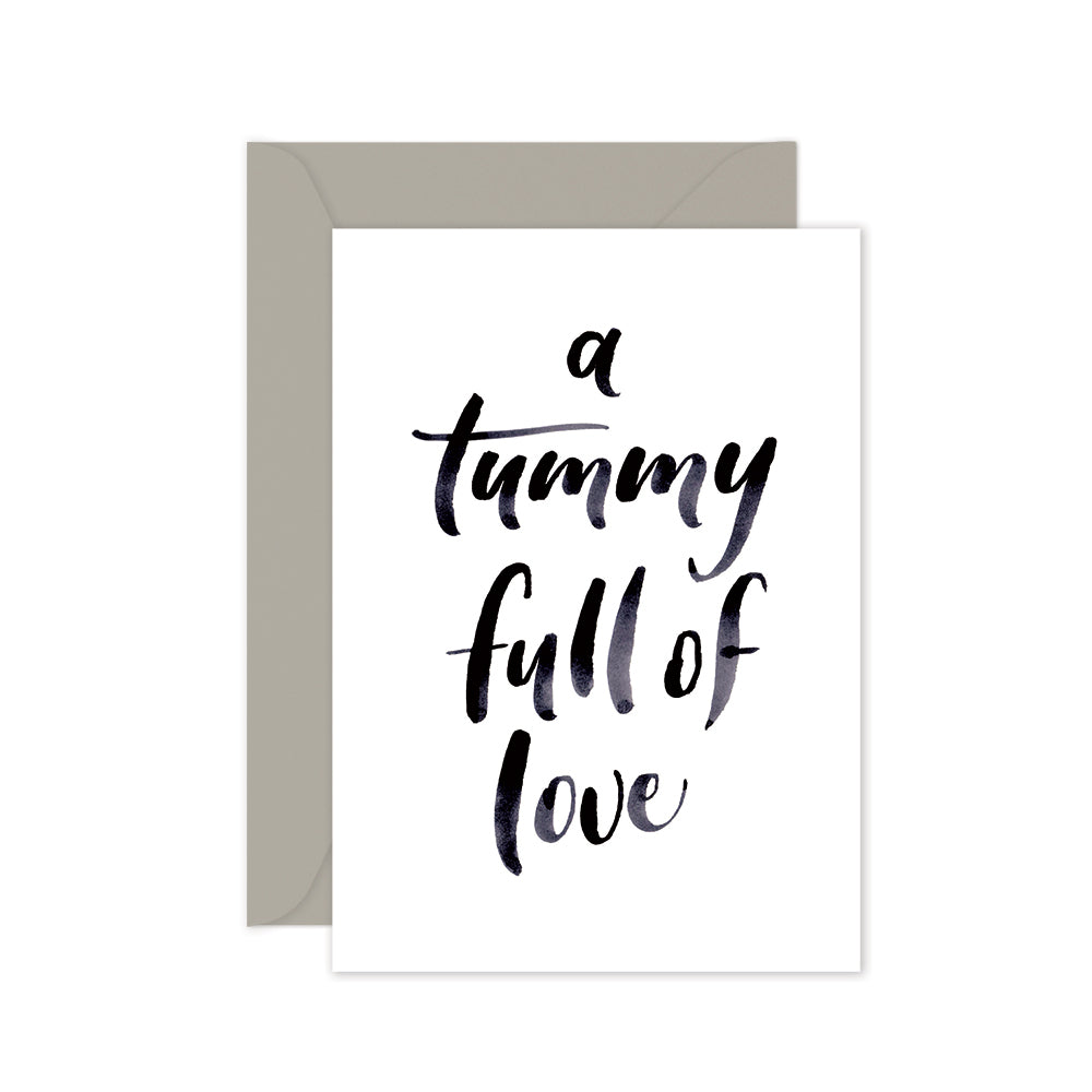 A greeting card with the phrase 'a tummy full of love' written in a cursive script, accompanied by a grey envelope, against a white background.