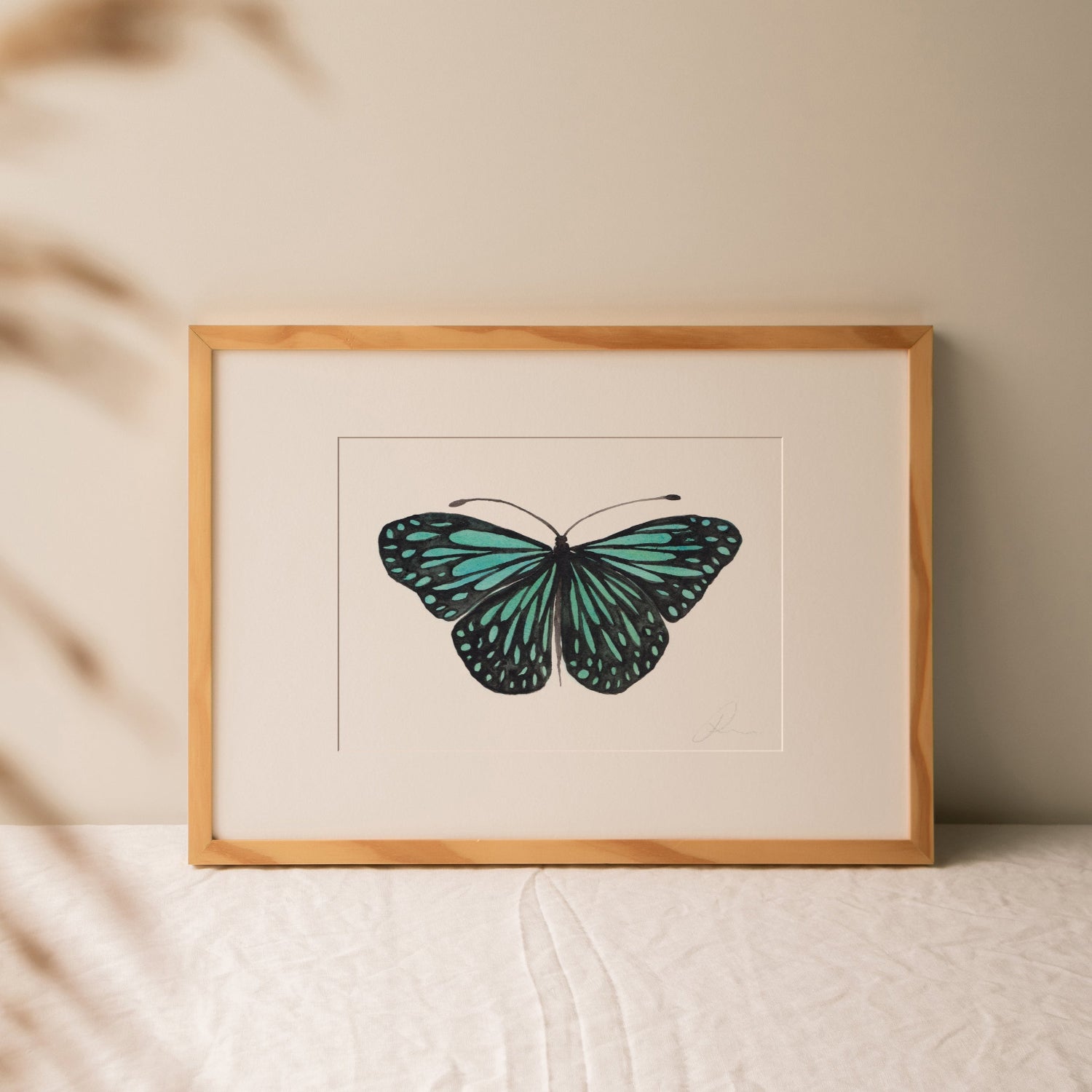 Framed artwork of a blue butterfly on a beige background