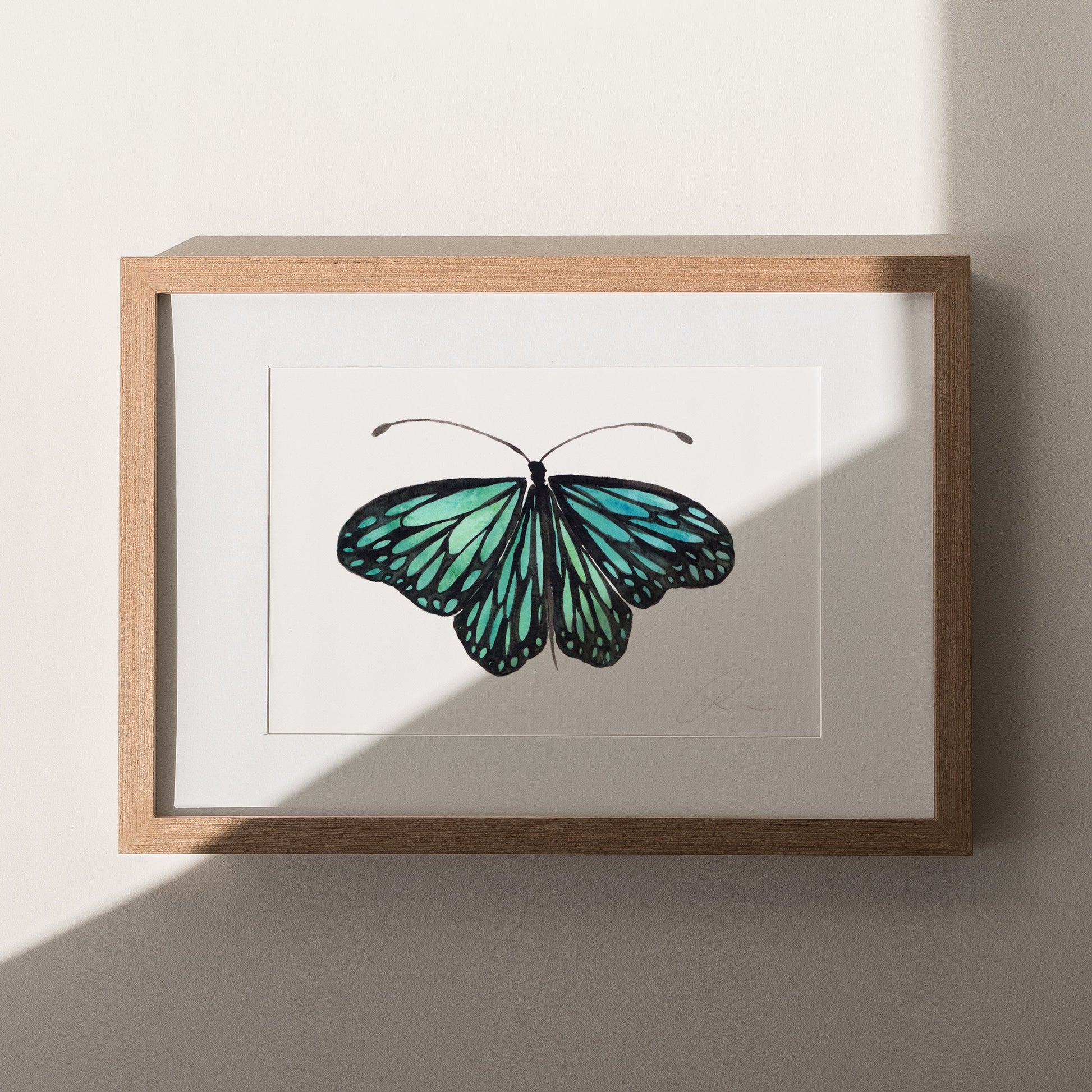 Framed artwork of a green butterfly on a white background
