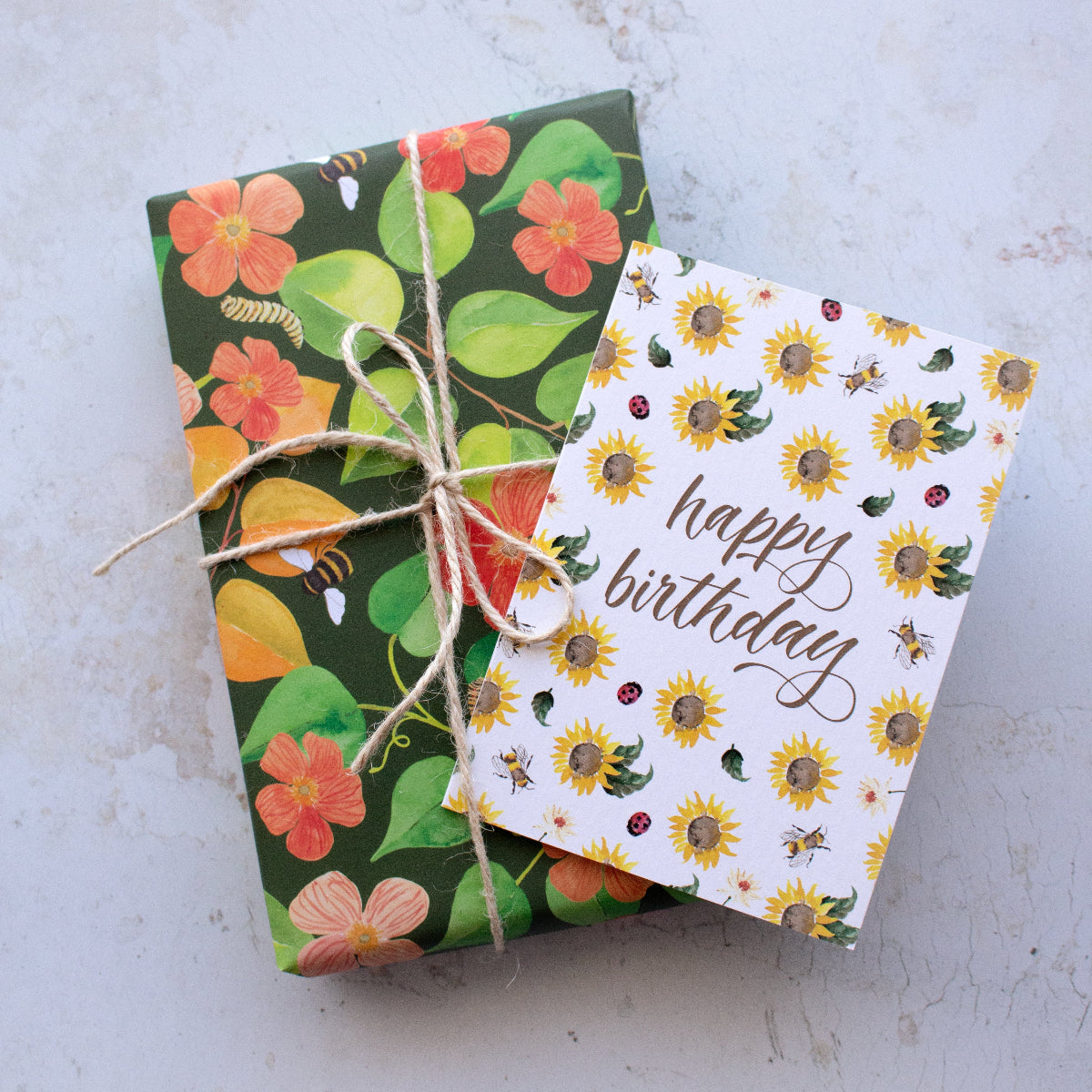 Sunflower happy birthday card ontop of a botanical wrapped present with string