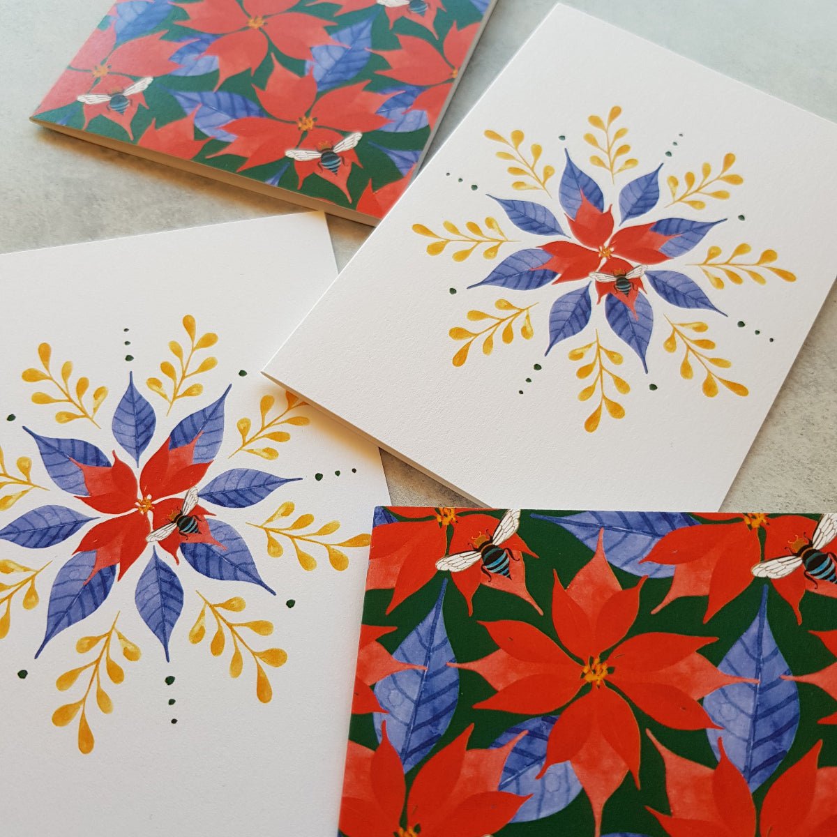 Four festive greeting cards with poinsettia and floral designs on a light background.
