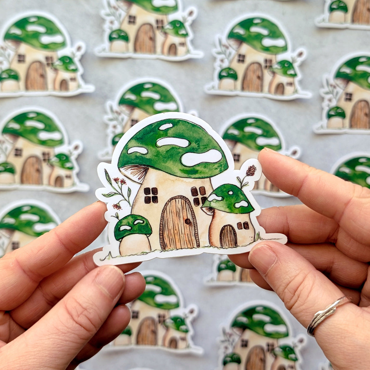 Mushroom house stickers held by a person with more stickers in the background