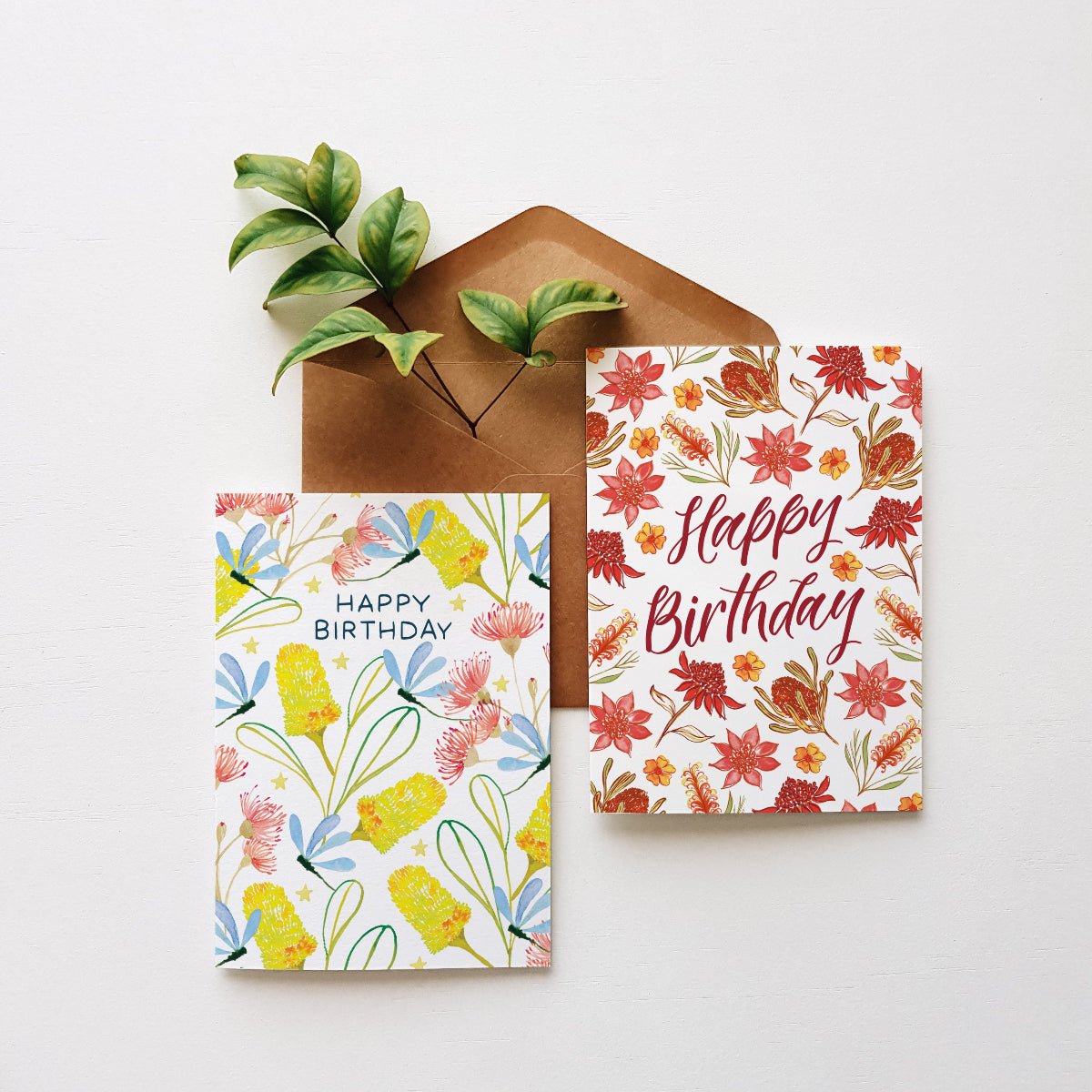 Two floral birthday cards with a brown envelope on a white background