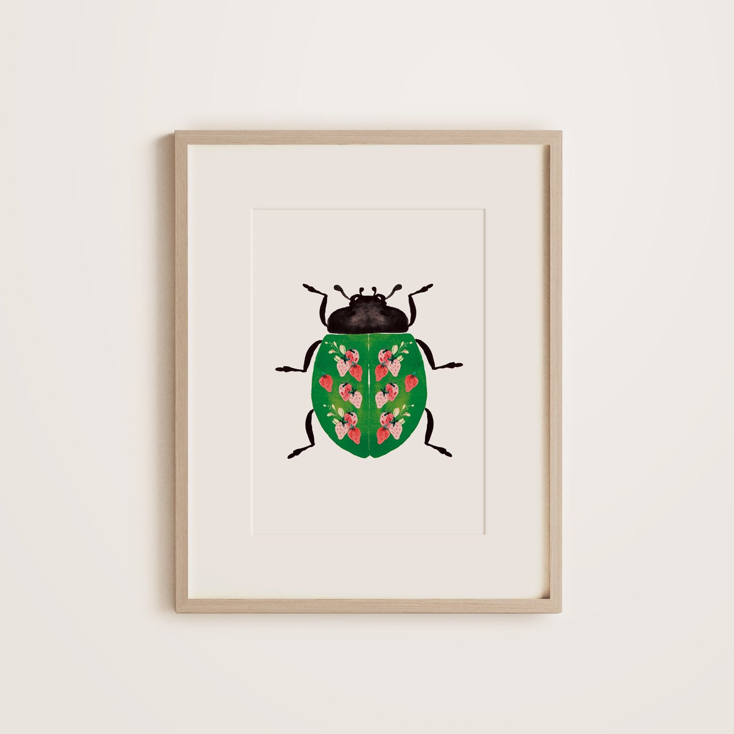 A wooden framed print featuring a ladybug with a strawberry pattern on the green shell