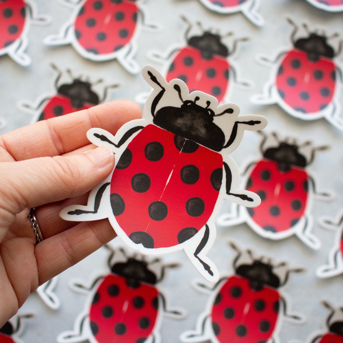 Hand holding a ladybug sticker with more ladybug stickers in the background