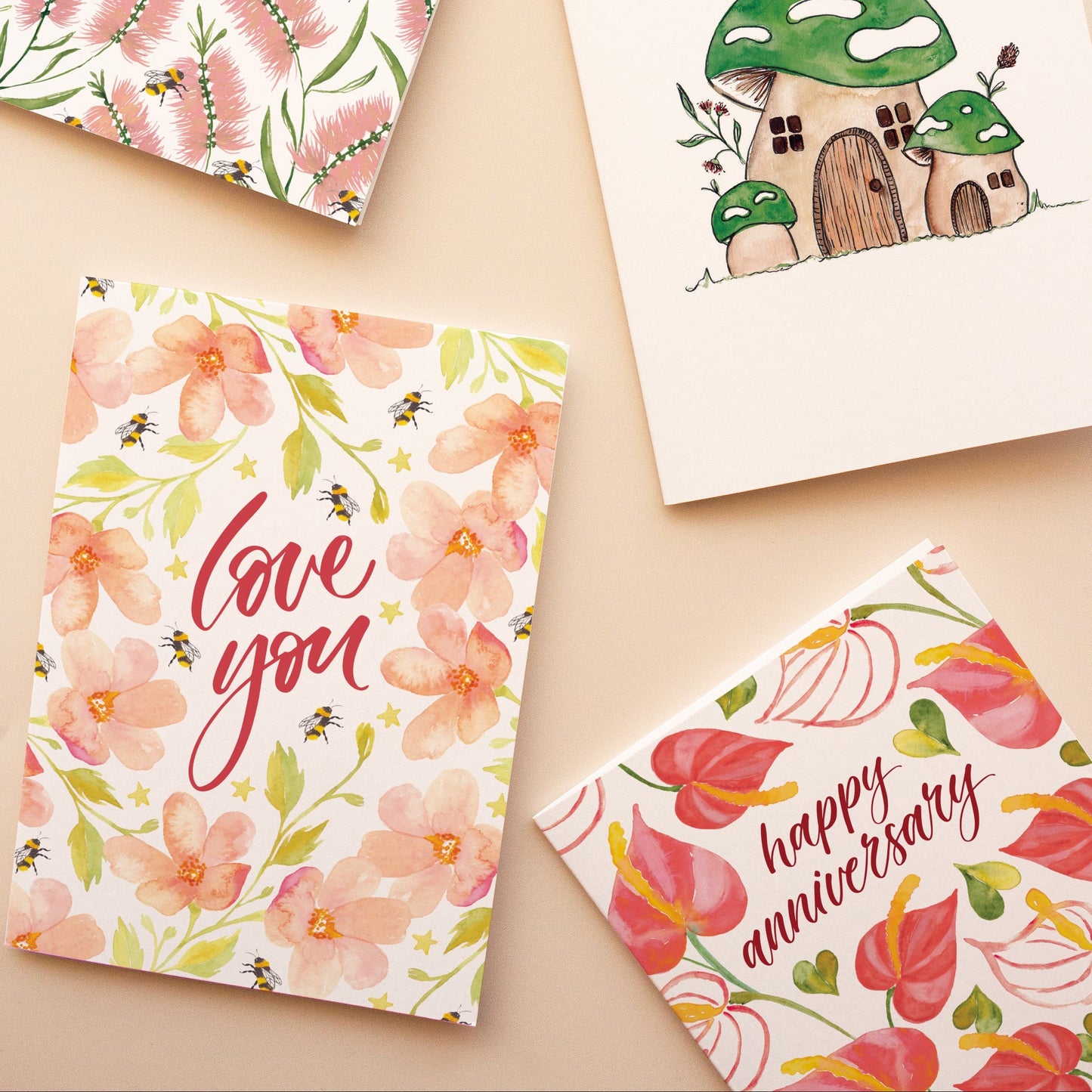 Four greeting cards with pink floral designs on a beige background