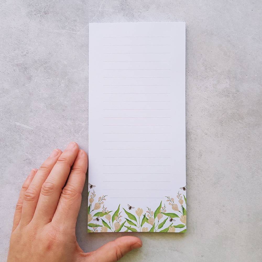 hand next to lined DL notepad design. Design creamy peach freesias and bees