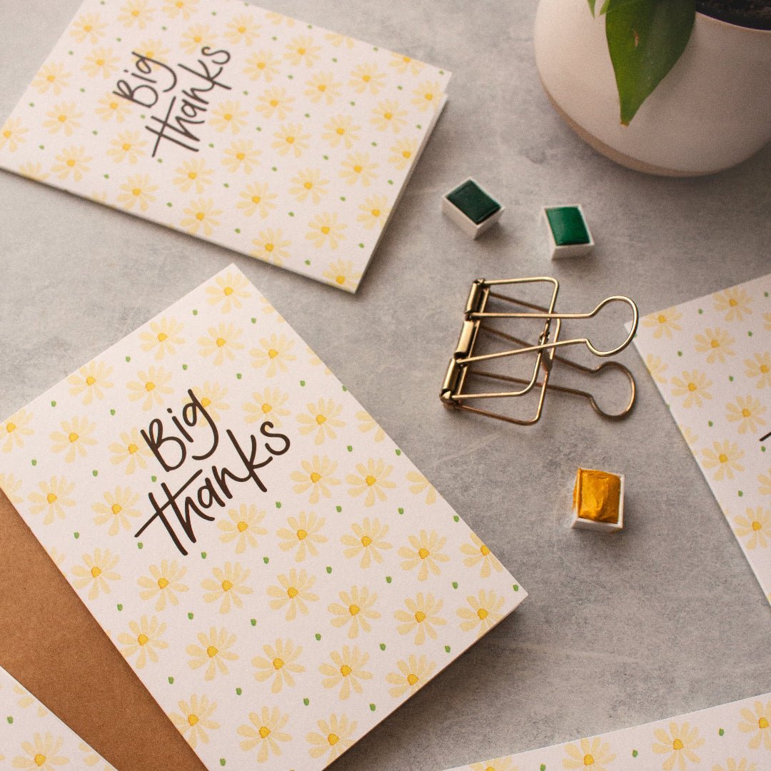 Thank you card with cream daisies, ‘Big Thanks’ text, kraft envelope, styled with bulldog clip.