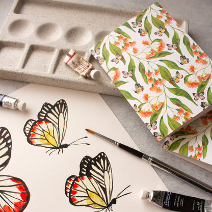 Butterfly illustrations on paper with a paint palette and tubes of paint.