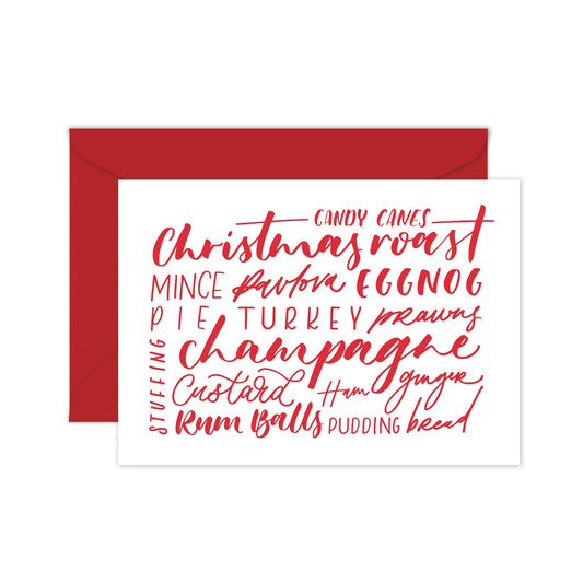 A folded white greeting card with red text, listing various Christmas-related phrases, and a red envelope. 