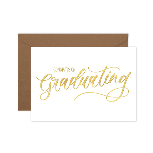 Graduation card with gold text 'Congrats on Graduating' and brown envelope on a white background