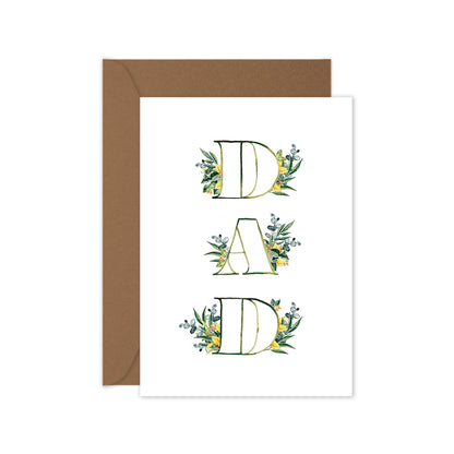 A greeting card with the word 'DAD' surrounded by leaf designs, folded with a brown envelope.
