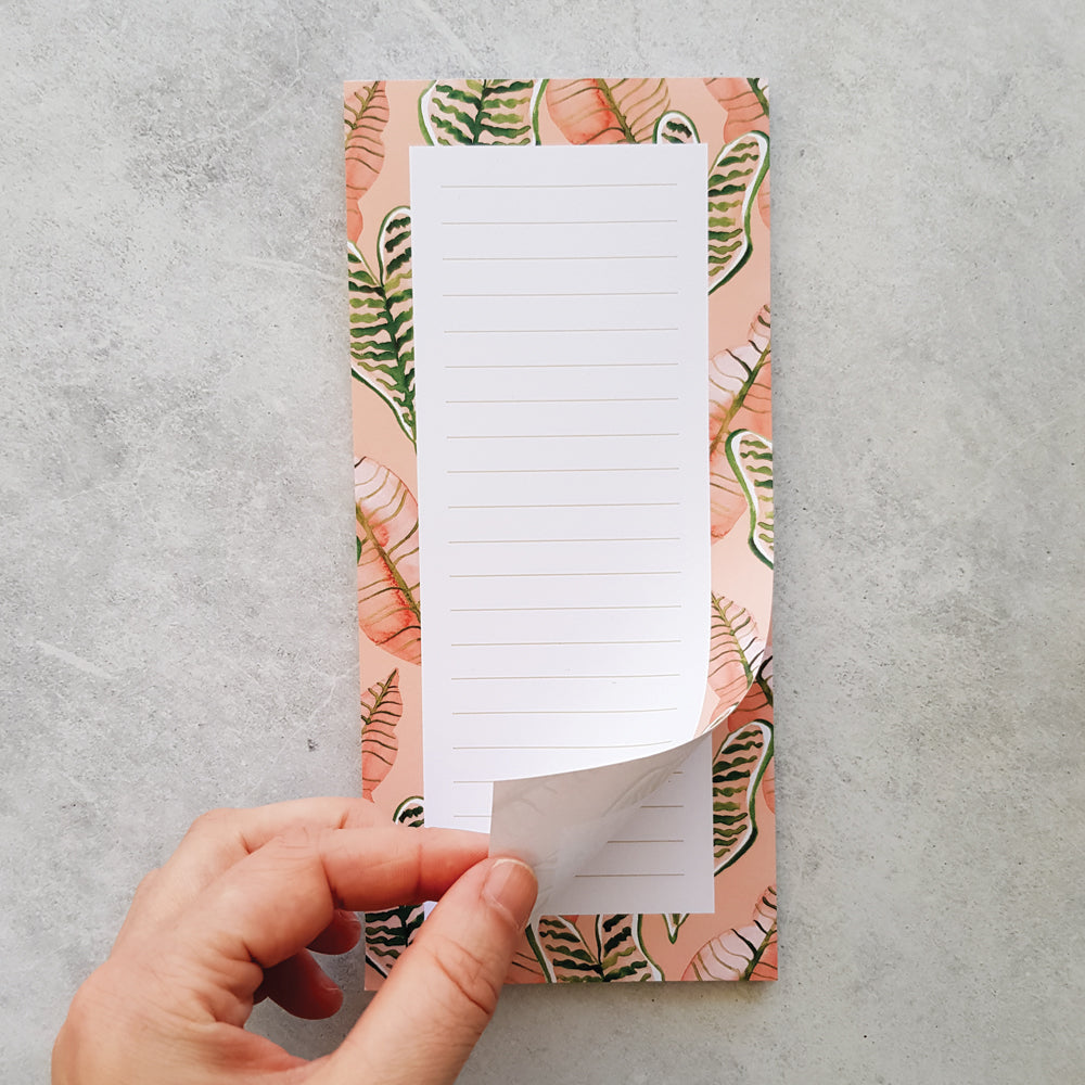 hand turning page on watercolour pink and green jungle leaves lined DL notepad