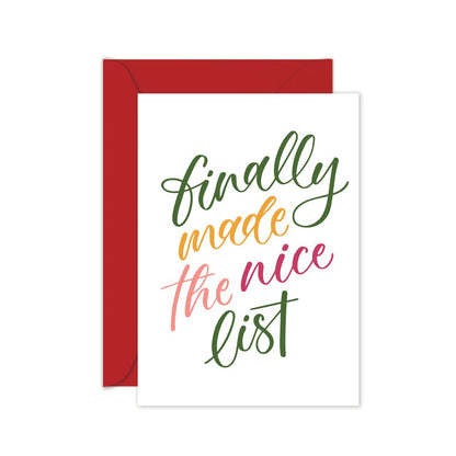 A folded greeting card with a white background and red envelope. The card has green and pink text that reads 'Finally made the NICE LIST' in a cursive script.