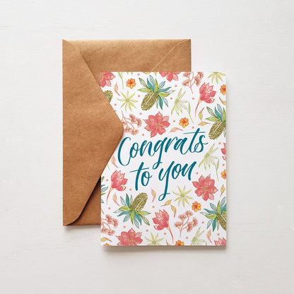 Floral congratulatory card with 'Congrats to you' text and brown envelope on a light gray background