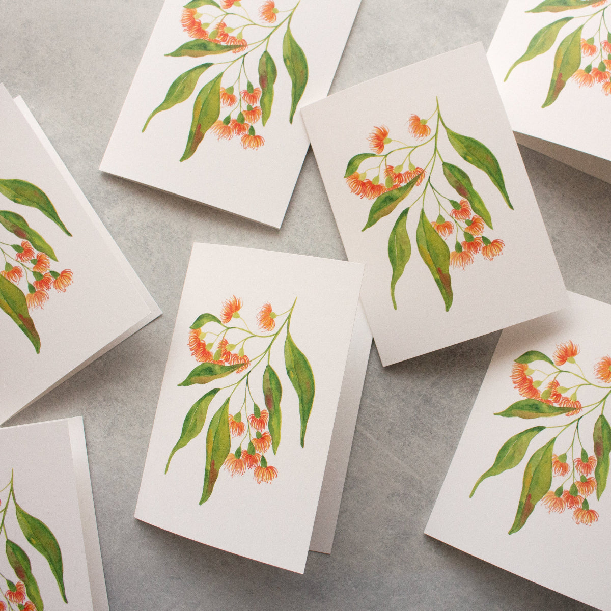 White cards with orange floral designs on a grey surface