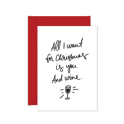 A white greeting card with the text 'All I want for Christmas is you. and wine.' with a red envelope