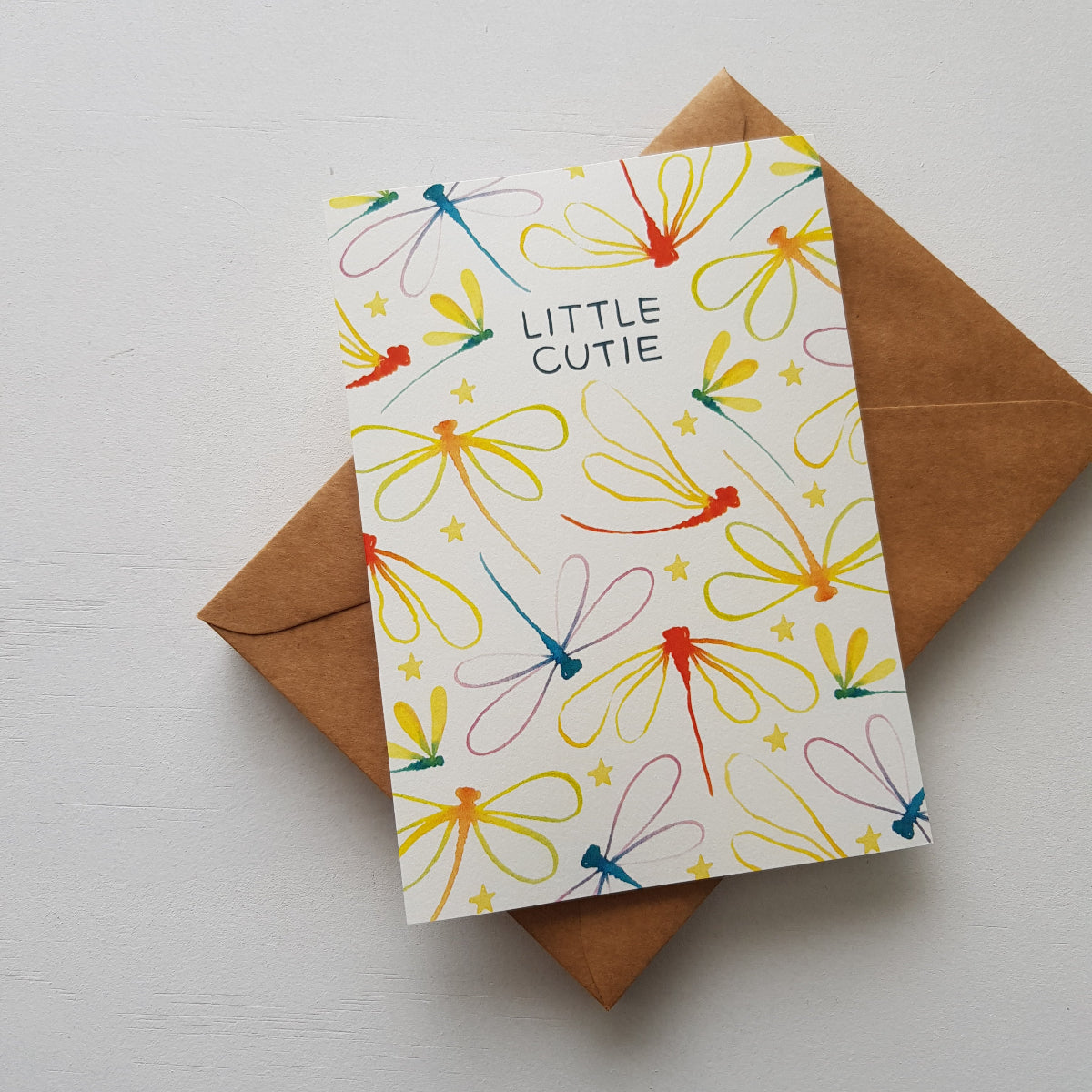 Baby greeting card with colourful dragonflies and stars on a brown envelope