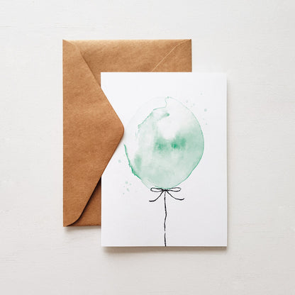 green ballon birthday greeting card on a white background with a kraft envelope