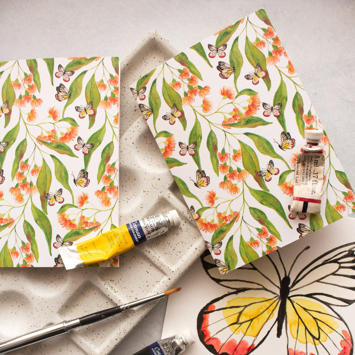Butterfly-themed greeting cardswith paint tubes and brushes on a light background