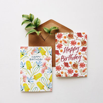 Two floral birthday cards with a brown envelope on a white background