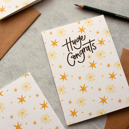Huge Congrats congratulations card featuring flowers and stars, styled with a pencil and envelopes. 