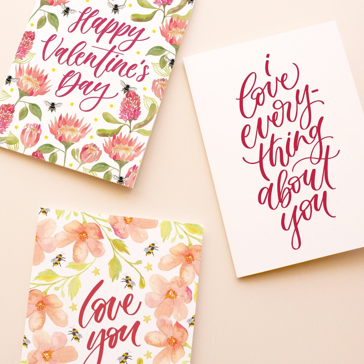 Three Valentine's Day greeting cards arranged on a light beige background. 