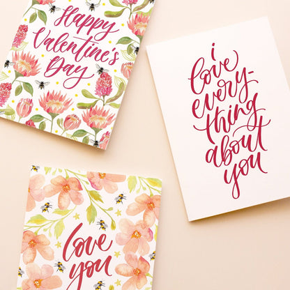 Three Valentine's Day greeting cards arranged on a light beige background. 