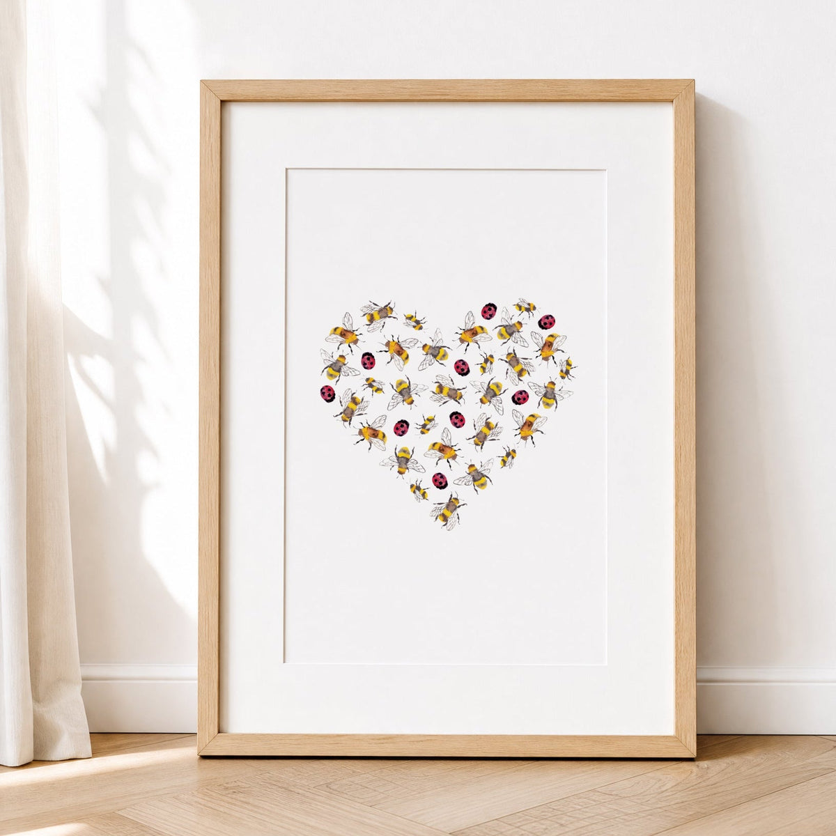 Framed artwork with a heart design of lady bugsand bees on a white wall.