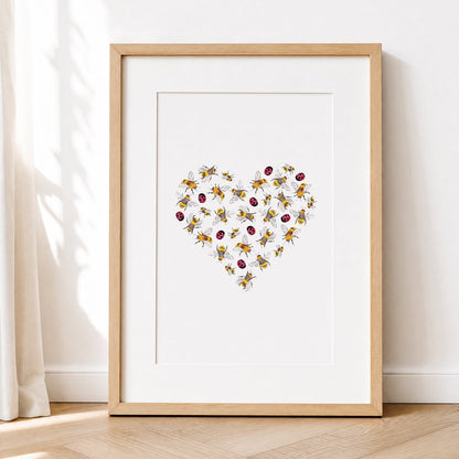 Framed artwork with a heart design of lady bugsand bees on a white wall.