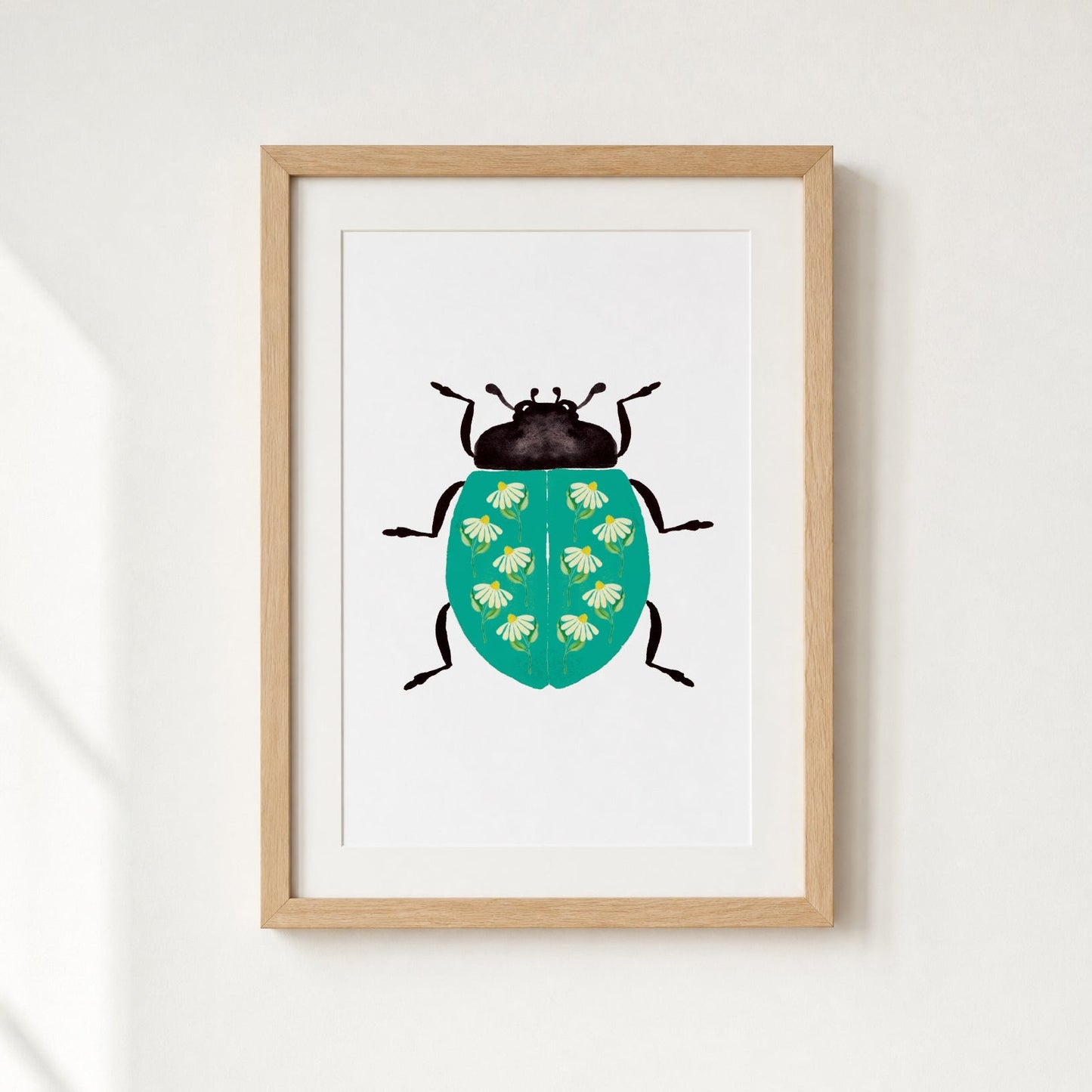 Framed artwork of a teal ladybug with daisies on a white wall.