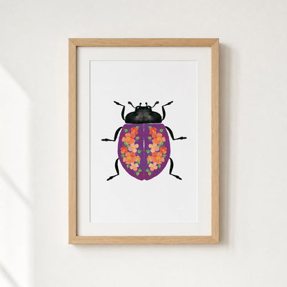 Framed artwork of a purple beetle with flowers on it's shell
