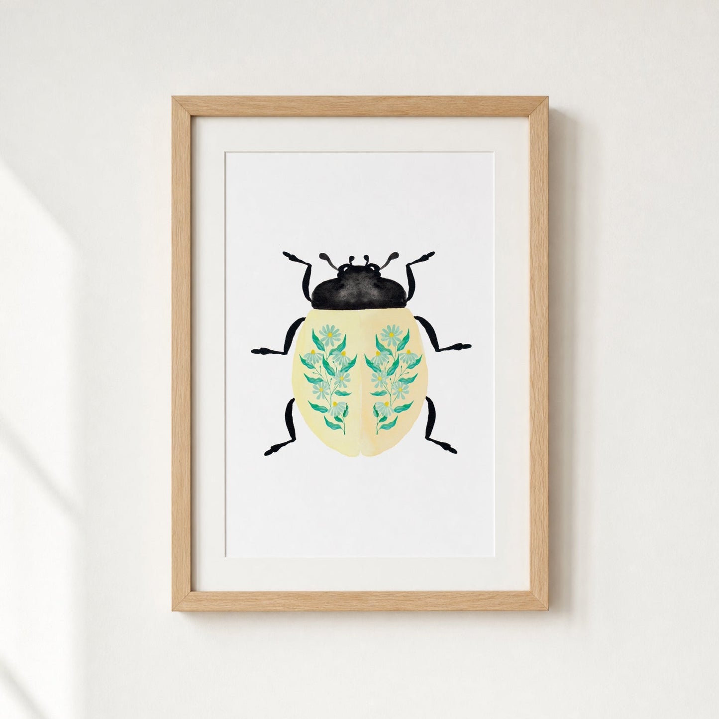 Framed artwork of a beetle with floral patterns on a white wall