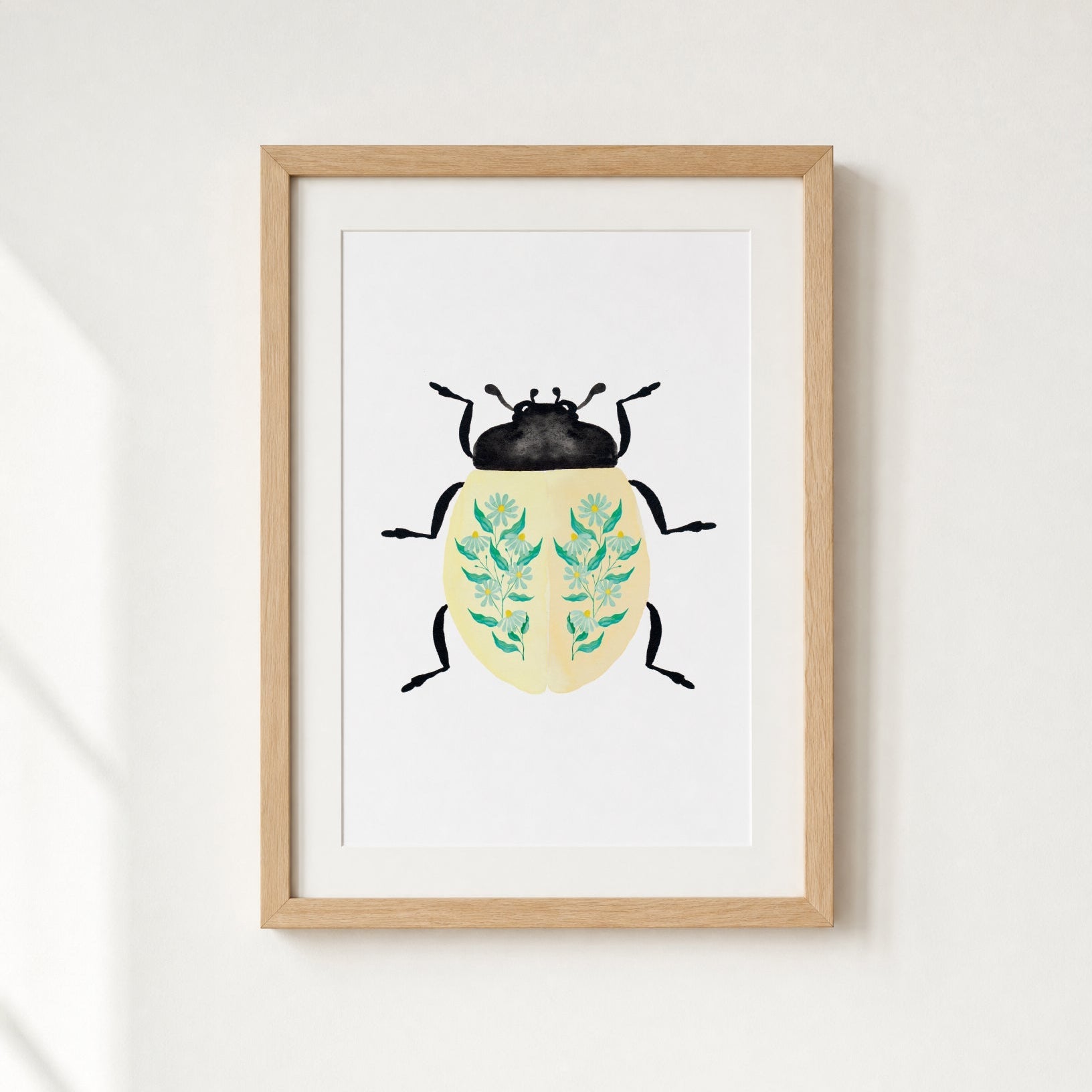Framed artwork of a beetle with floral patterns on a white wall