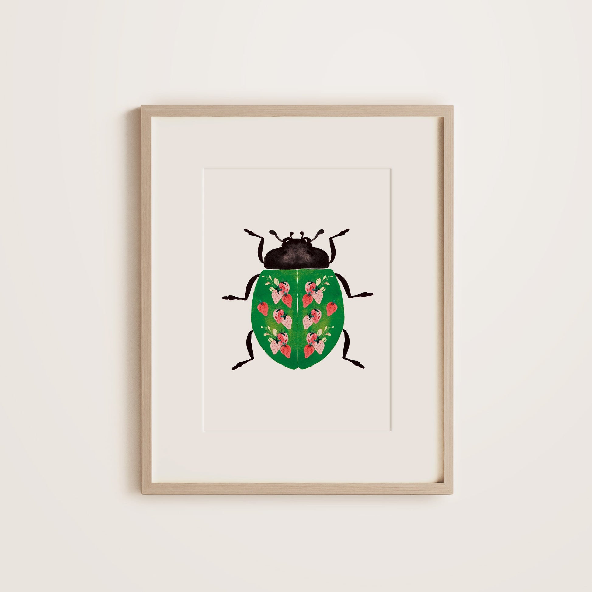 A wooden framed print featuring a ladybug with a strawberry pattern on the green shell