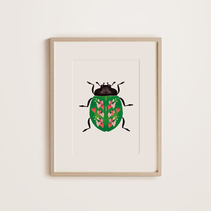 A wooden framed print featuring a ladybug with a strawberry pattern on the green shell