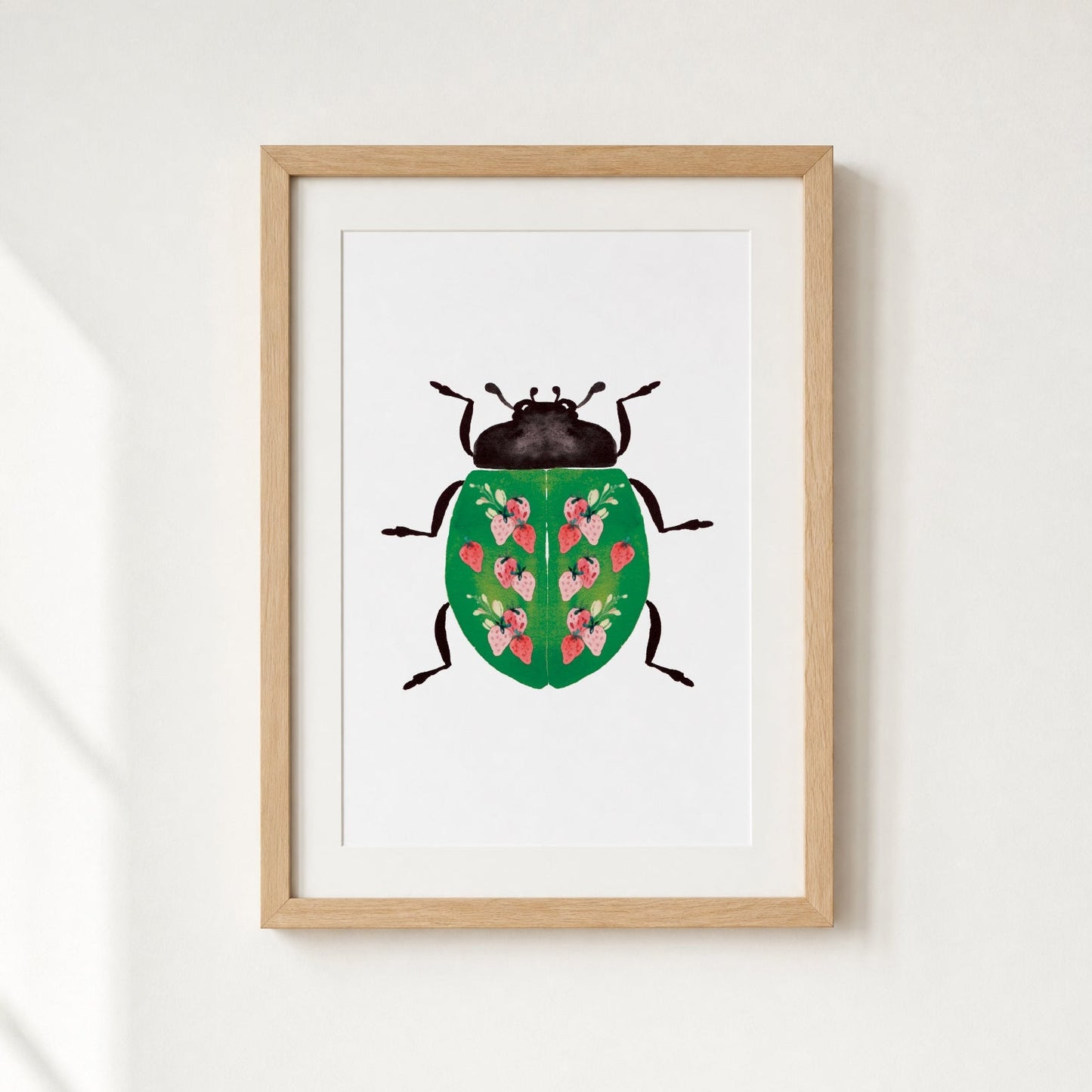 Framed artwork of a beetle with strawberries design on a white wall