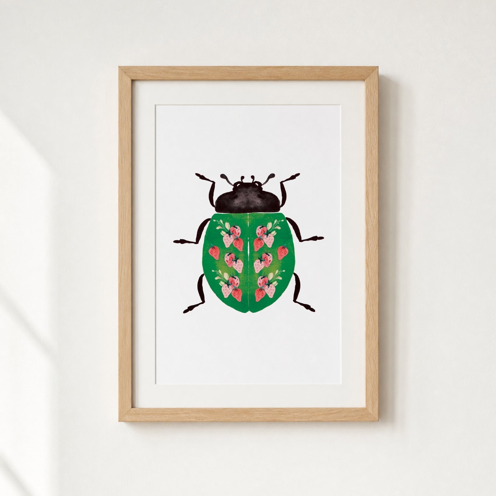 Framed artwork of a beetle with strawberries design on a white wall