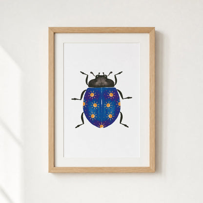 Framed artwork of a blue beetle with yellow suns on a white wall