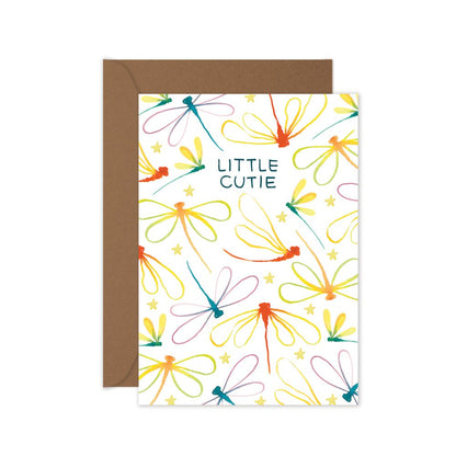 A colorful baby greeting card with dragonfly aand the text 'LITTLE CUTIE' and a brown envelope.