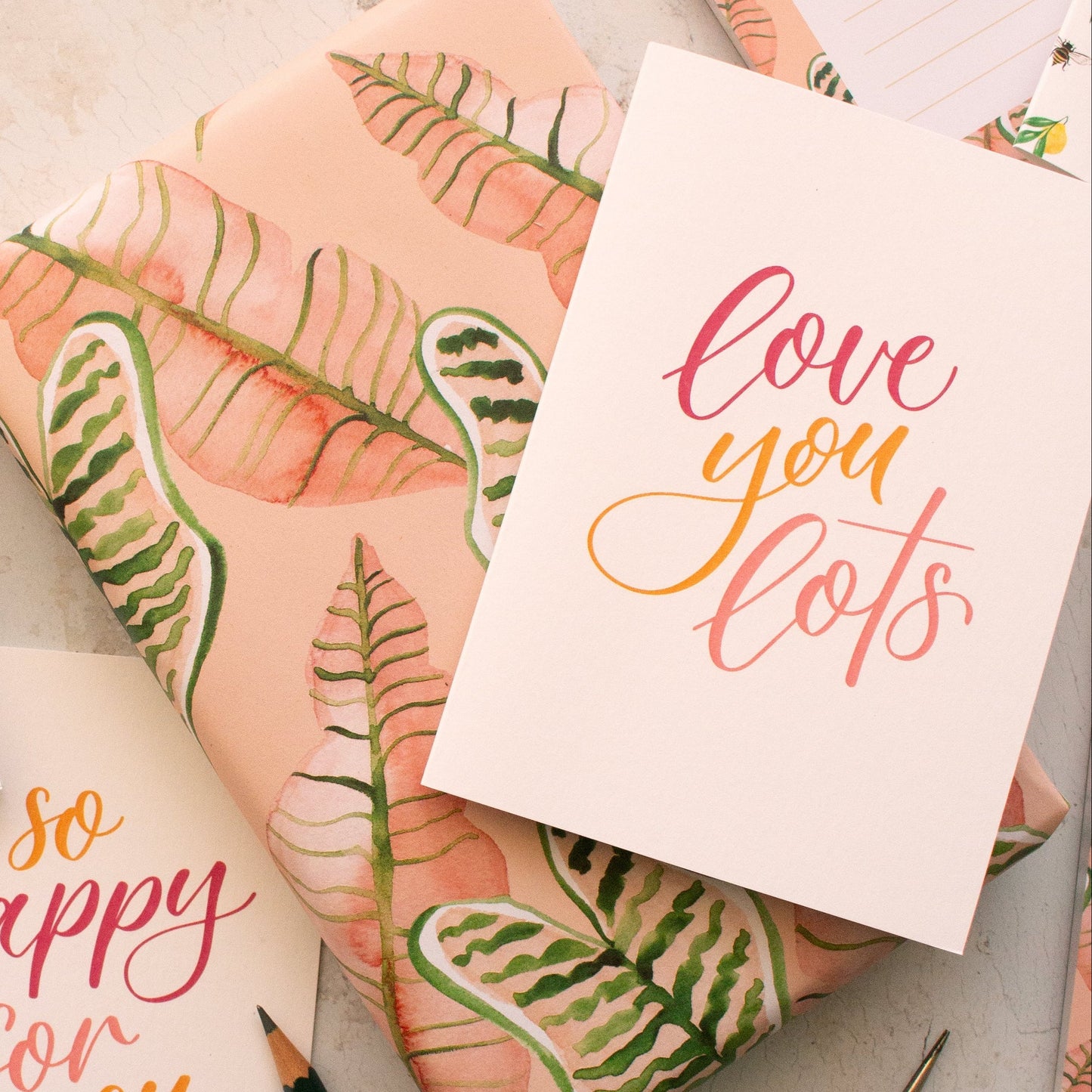 Greeting cards with floral designs and text on a textured surface with stationery items.