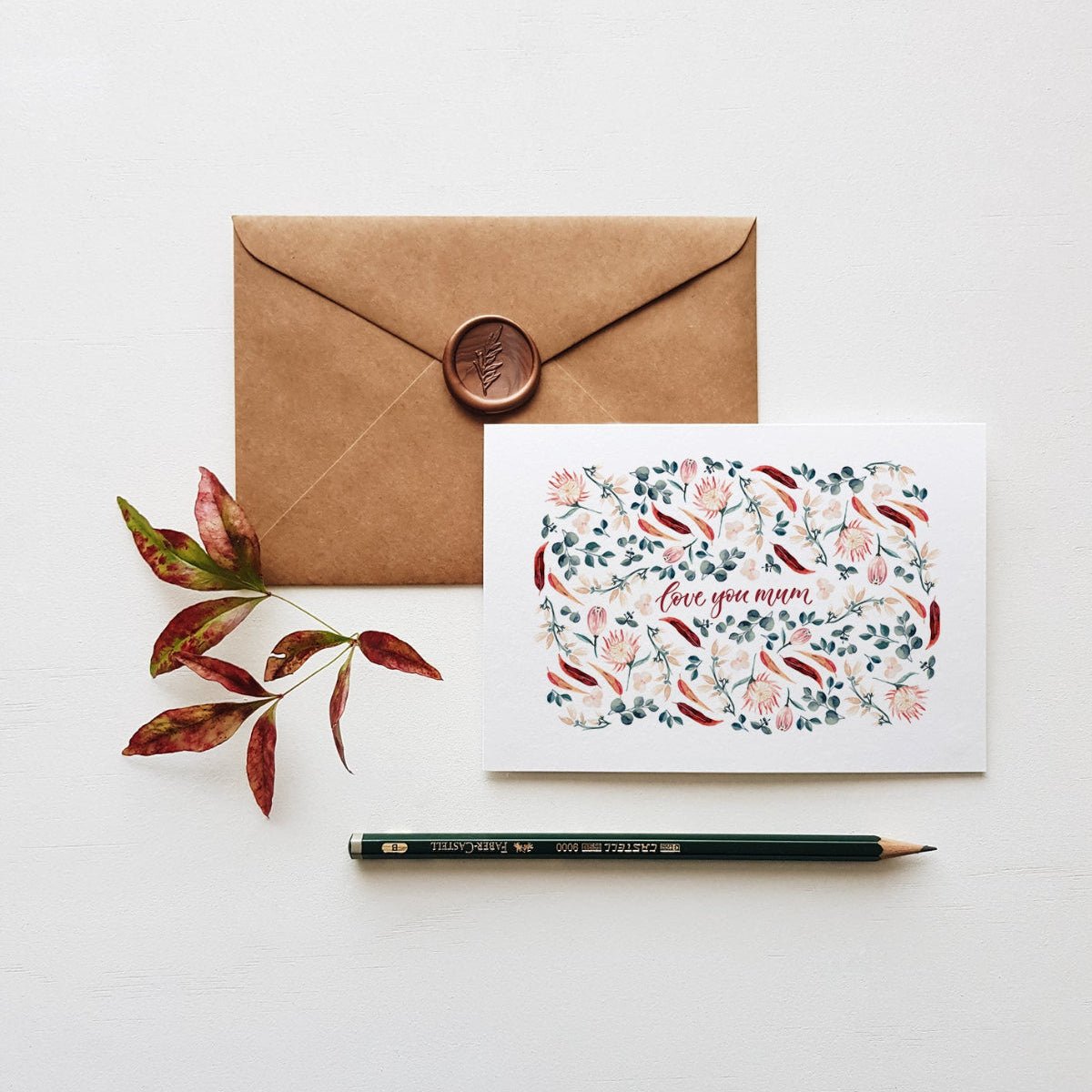 floral mum greeting card with brown envelope, wax seal, pencil and leaves