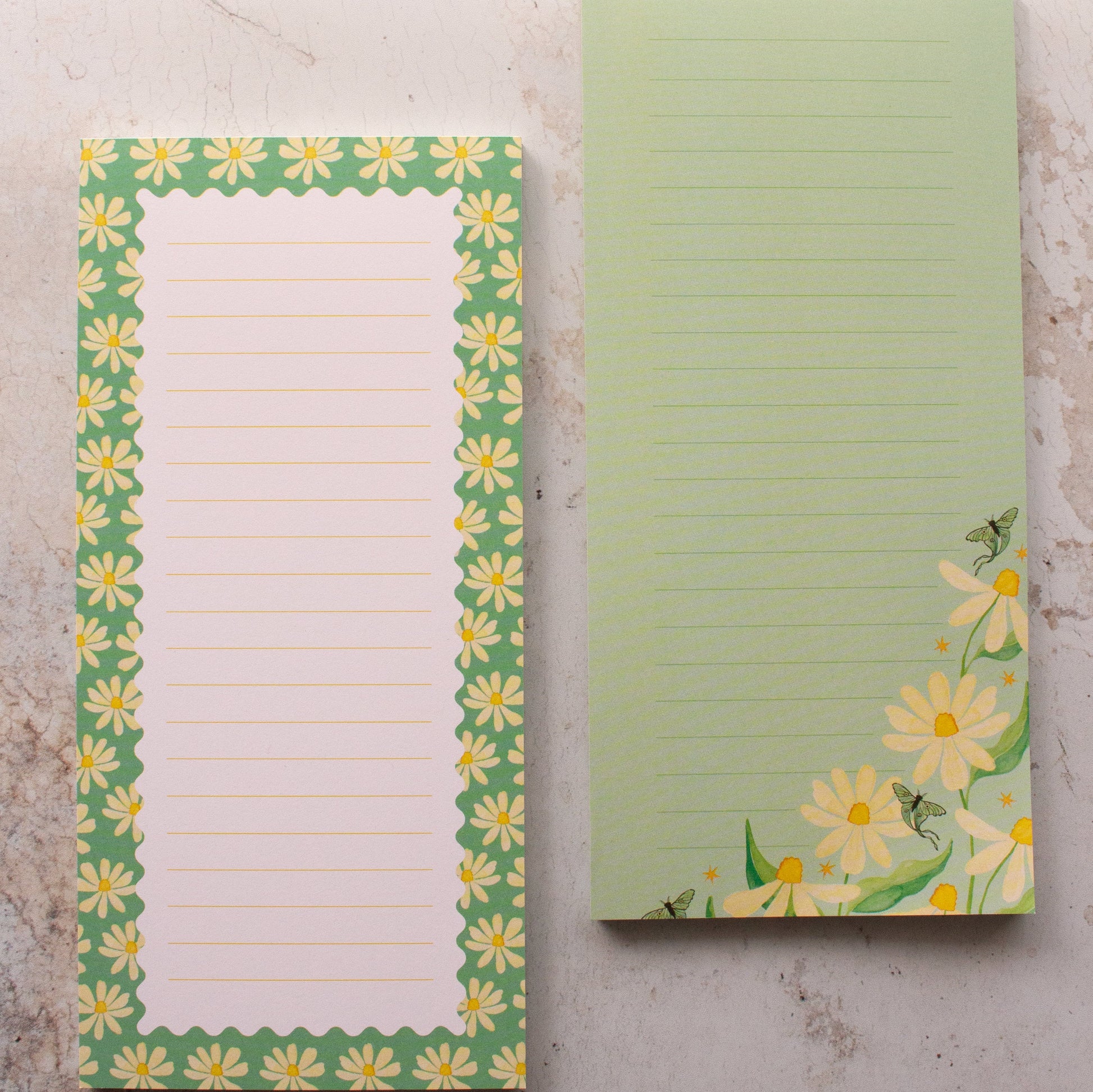 Two notepads with floral designs on a marble surface