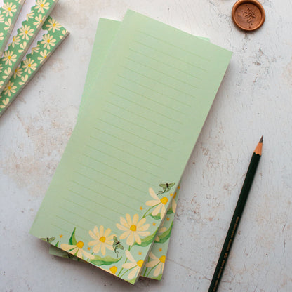 Green notepads with floral designs on a textured surface with a pencil.