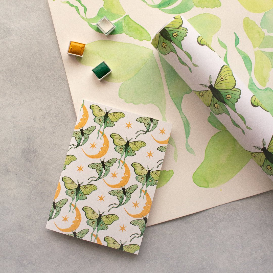 Luna moth patterned paper and stamps on a grey surface