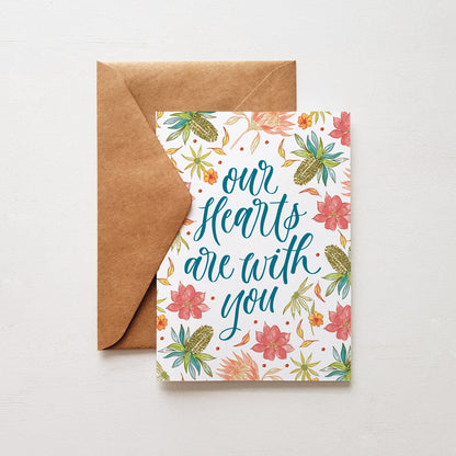 botanical sympathy greeting card with the words 'our hearts are with you'. Brown envelope on a white background
