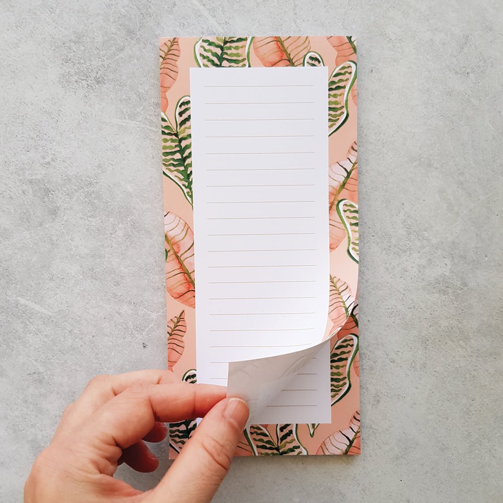 hand turning page on watercolour pink and green jungle leaves lined DL notepad