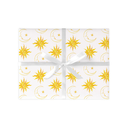 Wrapped gift on a white background with yellow suns and moons repeat pattern. Present tied together with a white ribbon.