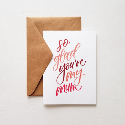 Greeting card with the words so glad you're my mum' with a brown envelope on a white background